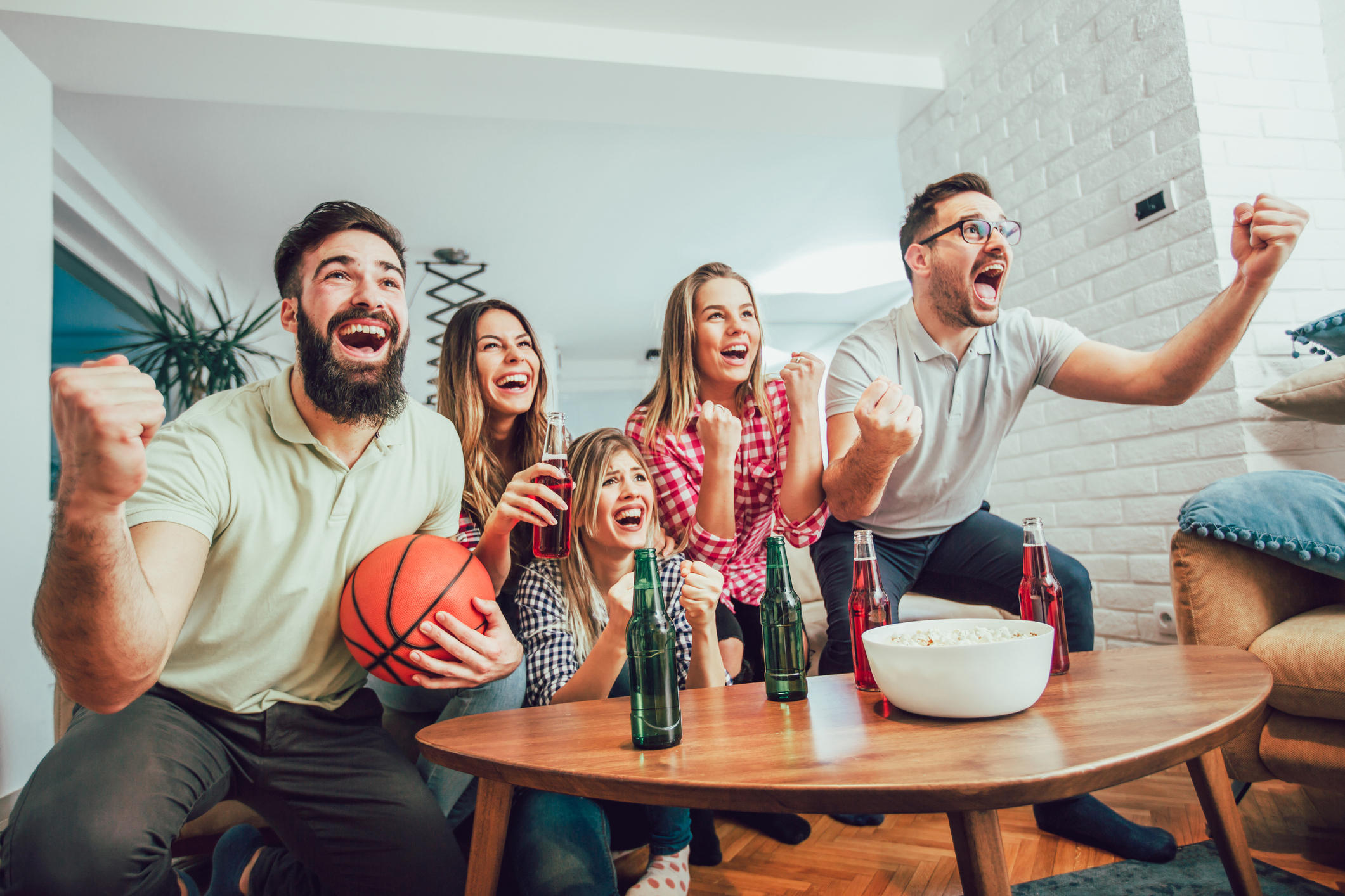 Happy friends or basketball fans watching basketball game on tv and celebrating victory at home.Friendship, sports and entertainment concept.